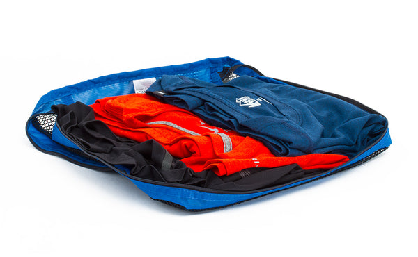 An open Medium Tri-Star Packing Cube in Island (blue) 120 Aether filled with shirts.